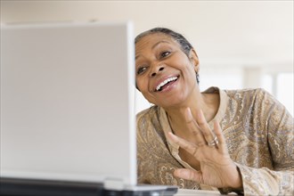 Mixed race woman using laptop at table