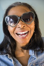 Mixed race woman wearing heart-shaped sunglasses