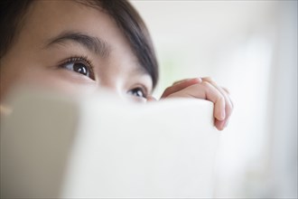 Close up of Filipino girl peering over chair back