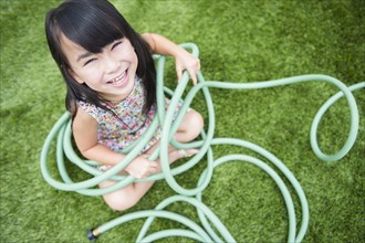 Filipino girl playing with hose in backyard