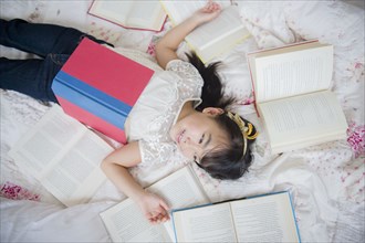 Filipino girl laying in bed with books