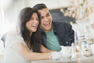 Hispanic couple laughing in cafe