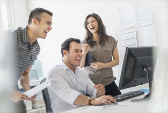 Hispanic business people laughing together in office