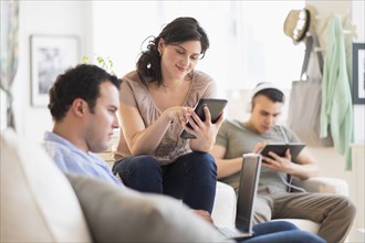 Hispanic friends using technology in living room