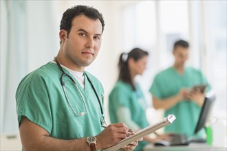 Hispanic nurse reading medical chart in hospital