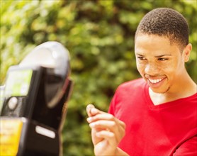 African American man paying parking meter