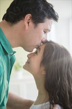 Hispanic father kissing daughter on forehead