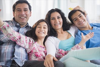 Hispanic family smiling together on sofa