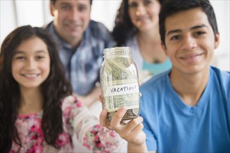 Hispanic family holding full vacation savings jar