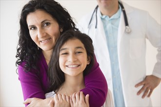 Hispanic mother and daughter smiling with doctor