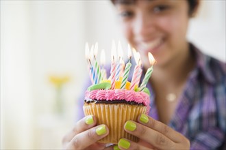 Mixed race woman holding cupcake with birthday candles