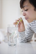 Mixed race woman drinking water with straw