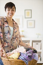 Mixed race woman holding basket of dirty laundry