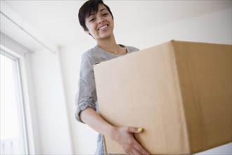 Smiling mixed race woman carrying cardboard box