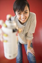 Smiling mixed race woman holding canister of spray paint