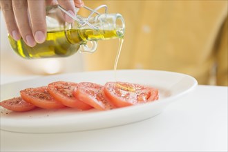 Close up of mixed race man pouring oil on tomatoes