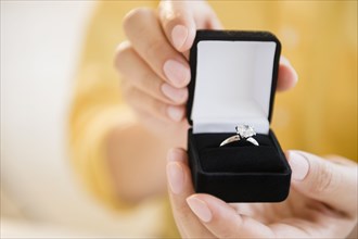 Mixed race man holding engagement ring in box