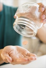 Close up of mixed race man pouring penny out of jar