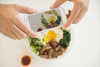 Close up of mixed race man photographing food with cell phone
