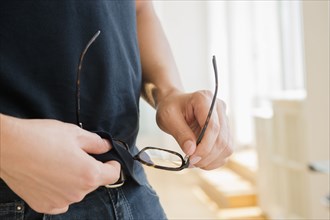 Close up of mixed race man cleaning eyeglasses with shirt