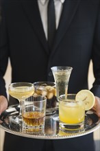 Close up of mixed race waiter holding tray of drinks