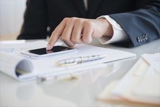 Close up of mixed race businessman using cell phone at desk