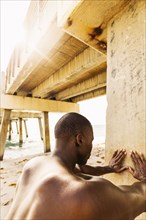 Mixed race man stretching under pier