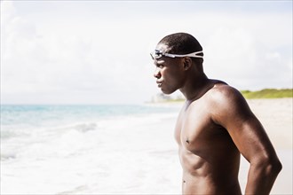 Mixed race swimmer wearing goggles at beach