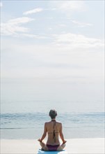 Caucasian woman meditating on beach