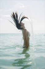 Caucasian woman splashing hair in ocean