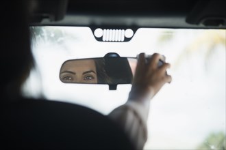 Caucasian woman adjusting rear view mirror in car