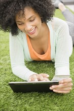 Woman using digital tablet on grassy lawn