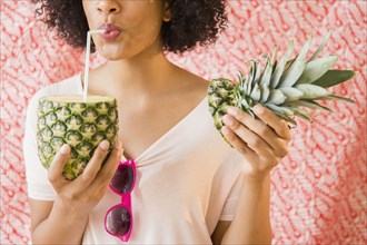 Woman drinking juice from fresh pineapple