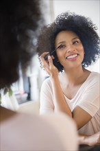 Smiling woman applying mascara in mirror