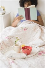Woman reading book and with breakfast in bed