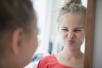 Caucasian girl scrunching up her face in mirror