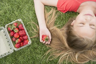 Caucasian girl holding strawberries on grassy lawn