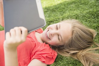 Caucasian girl using digital tablet on grassy lawn