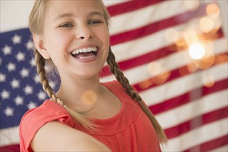 Caucasian girl holding sparkler by American flag