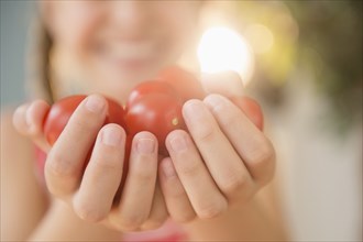 Close up of Caucasian girl holding handful of tomatoes