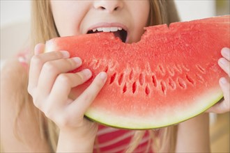Caucasian girl eating large slice of watermelon