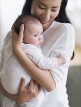 Smiling Asian mother holding baby