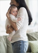 Asian mother holding baby in living room