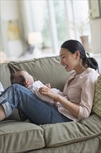 Asian mother playing with baby in living room