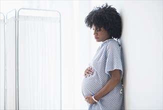 Pregnant African American mother holding stomach in hospital