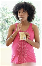 Pregnant African American mother eating ice cream from carton