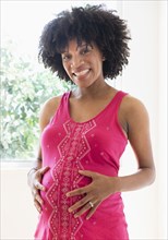Pregnant African American mother holding stomach