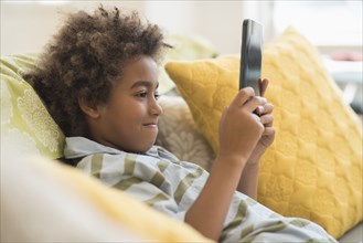 Mixed race boy using digital tablet in living room