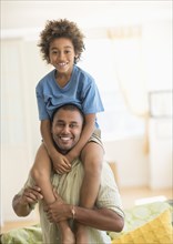 Father carrying son on shoulders in living room