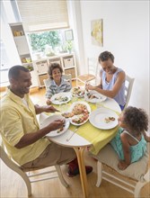 Mixed race family eating at dining room table